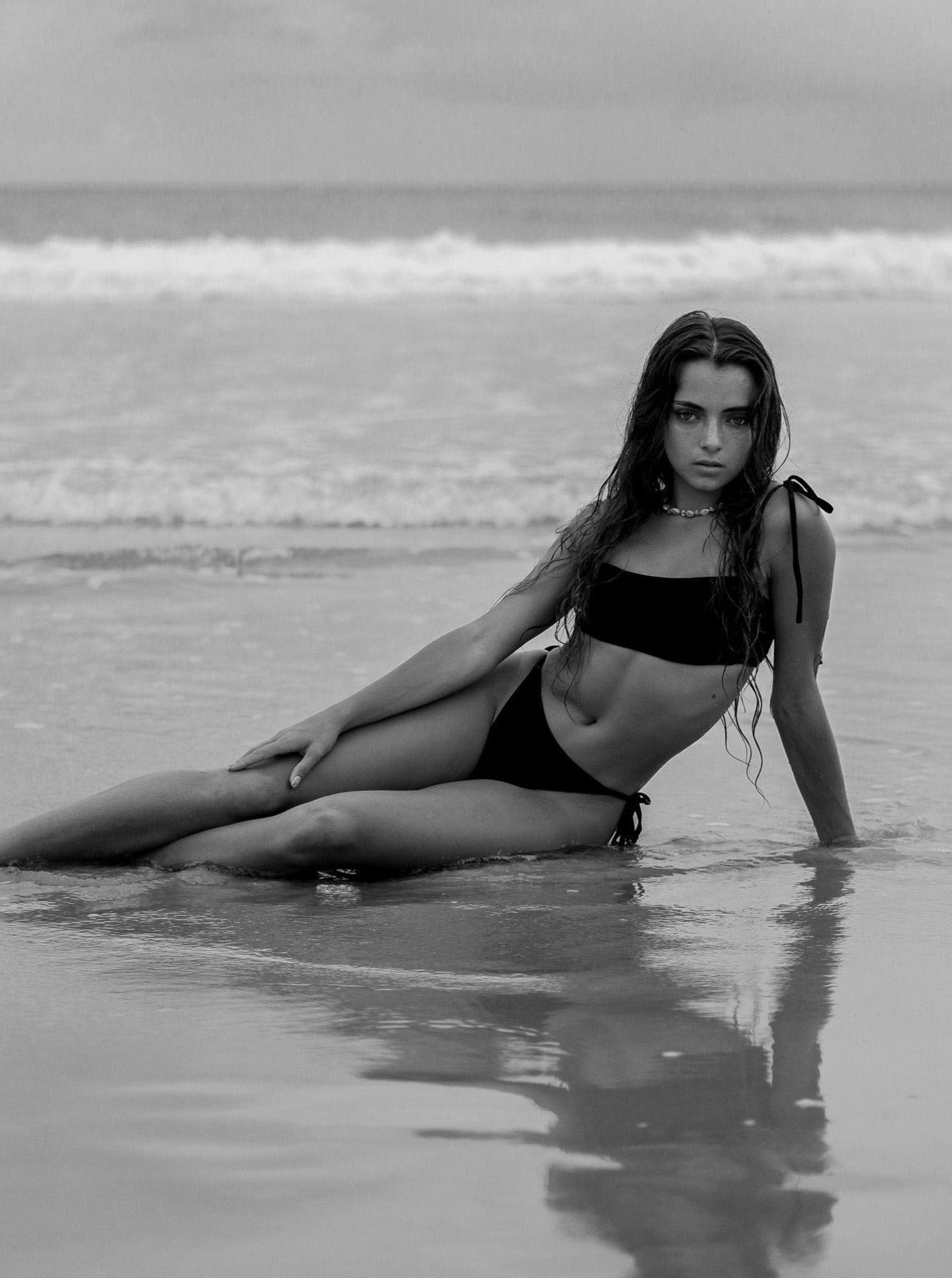 Model wearing the Maui black bikini top and Lolani tie bottom in a sunny beach setting